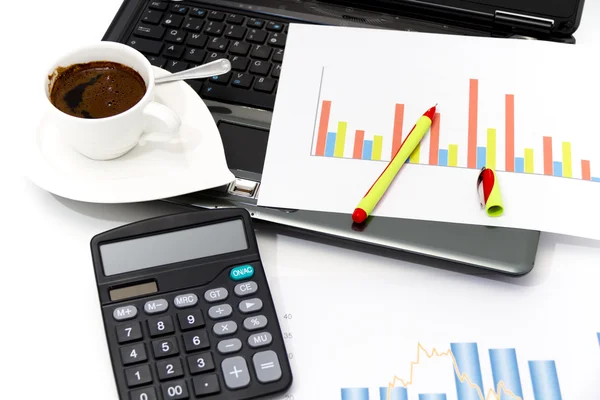 Analyzing business investment charts with calculator and laptop Stock Image