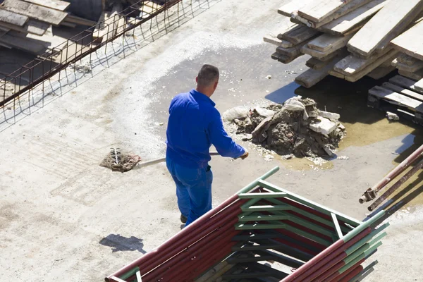 Werknemer werkt met een schop, schoonmaken puin Rechtenvrije Stockafbeeldingen