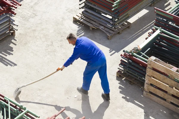 Lavoratore lavora con una pala, pulendo macerie — Foto Stock