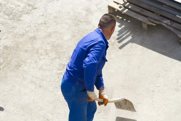 Lavoratore lavora con una pala, pulendo macerie — Foto Stock
