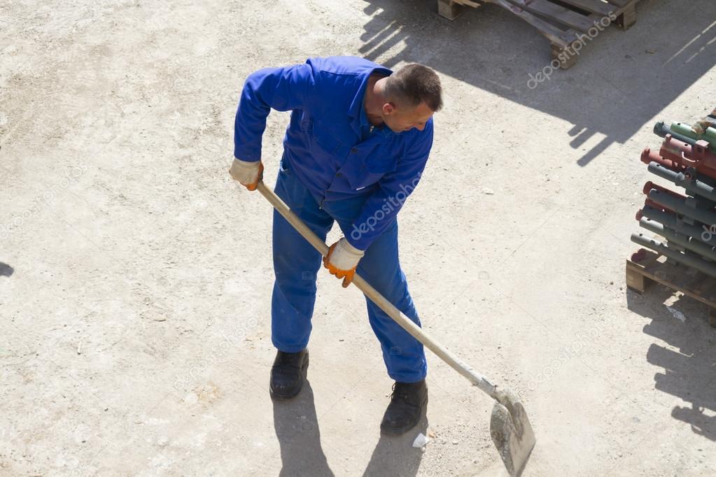 Worker works with a shovel, cleaning rubble