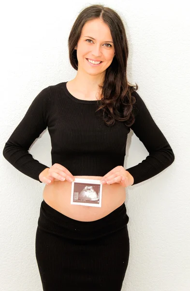 Zwangere vrouw genieten van kijken naar echografie van baby — Stockfoto