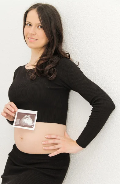 La mujer embarazada disfruta mirando la ecografía del bebé. — Foto de Stock