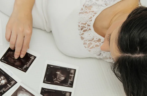 Těhotná žena si při pohledu na ultrazvukové vyšetření dítěte — Stock fotografie