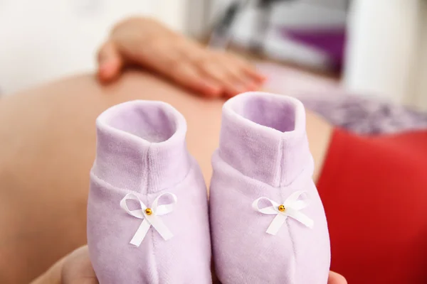 Femme enceinte avec des chaussures de bébé — Photo