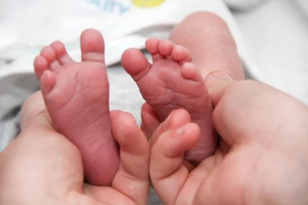 母の手で赤ちゃんの足、生まれたばかりの赤ちゃんが少し足します。 — ストック写真