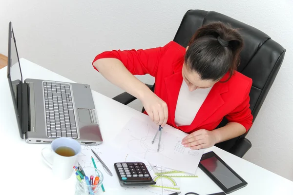 Young female designer working with architectural plan — Stock Photo, Image