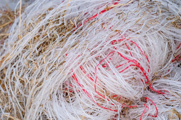 Pile of garbage, plastic threads of packing material of straw in a large pile. many colors of waste plastic outside on a farm.