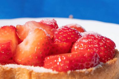 Beyaz tepside şekerli çilekli bir rusks. mavi arka plan. Seçici odak.