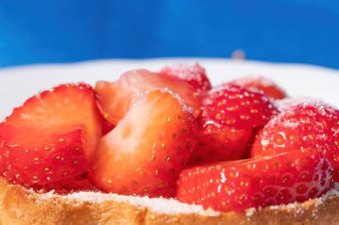 Beyaz tepside şekerli çilekli bir rusks. mavi arka plan. Seçici odak.