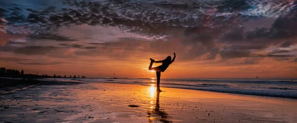 Πανόραμα σιλουέτας γυναίκας που κάνει γιόγκα στην παραλία κατά τη διάρκεια ενός όμορφου ηλιοβασιλέματος. μακρύ εξώφυλλο ή μέσα κοινωνικής δικτύωσης — Φωτογραφία Αρχείου
