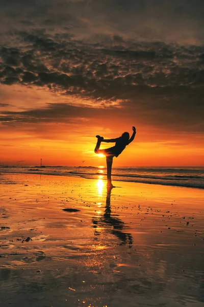 Νεαρή γυναίκα σιλουέτα, εξάσκηση γιόγκα στην παραλία της θάλασσας το ηλιοβασίλεμα — Φωτογραφία Αρχείου