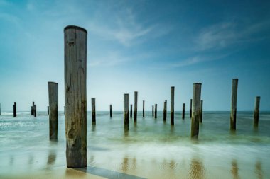 Geçmişe dönük renklerde uzun deniz manzarası. Petten 'de Kuzey Denizi' nde deniz kenarındaki kutup köyü, mavi gökyüzü, güneş ve ayakkabı ile çekildi. Önplana odaklan