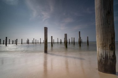 Geçmişe dönük renklerde uzun deniz manzarası. Petten 'de Kuzey Denizi' nde deniz kenarındaki kutup köyü, mavi gökyüzü, güneş ve ayakkabı ile çekildi. Önplana odaklan
