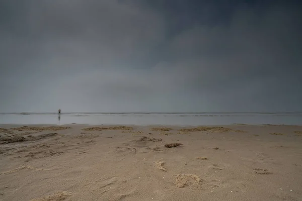 Θαλάσσιο τοπίο με θολή ανθρώπους που περπατούν στο παρασκήνιο. Σιλουέτα ανθρώπων στην παραλία και στη θάλασσα. Vintage στυλ φωτογραφία. εστίαση σε νέα στοιχεία — Φωτογραφία Αρχείου