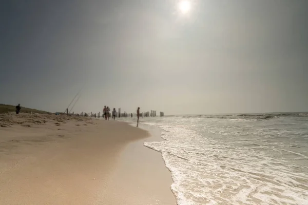 Zeegezicht met wazige mensen die op de achtergrond lopen. Silhouet van mensen op het strand en in de zee. Vintage stijl foto. focus op foreground — Stockfoto