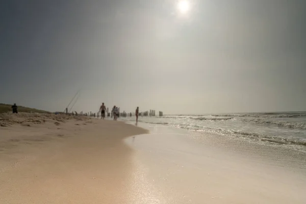 Zeegezicht met wazige mensen die op de achtergrond lopen. Silhouet van mensen op het strand en in de zee, mensen vissen. Vintage stijl foto. focus op foreground — Stockfoto