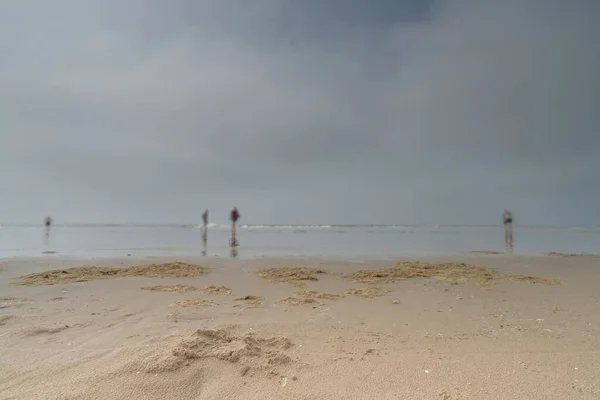 Zeegezicht met wazige mensen die op de achtergrond lopen. Silhouet van mensen op het strand en in de zee. Vintage stijl foto. focus op foreground — Stockfoto