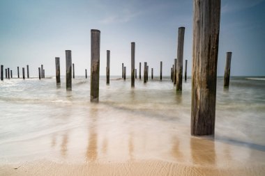 Geçmişe dönük renklerde uzun deniz manzarası. Petten 'de Kuzey Denizi' nde deniz kenarındaki kutup köyü, mavi gökyüzü, güneş ve ayakkabı ile çekildi. Önplana odaklan