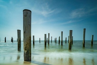 Uzun pozlu deniz manzarası. Petten 'de Kuzey Denizi' nde deniz kenarındaki kutup köyü, mavi gökyüzü, güneş ve ayakkabı ile çekildi. Önplana odaklan