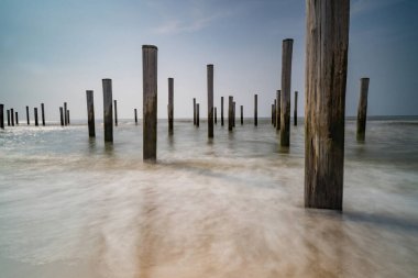 Geçmişe dönük renklerde uzun deniz manzarası. Petten 'de Kuzey Denizi' nde deniz kenarındaki kutup köyü, mavi gökyüzü, güneş ve ayakkabı ile çekildi. Önplana odaklan