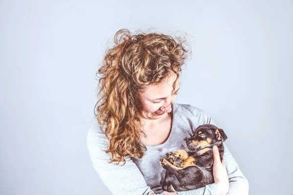 Parte de una hembra, con amor sostiene en sus brazos a un pequeño cachorro Jack Russel Terrier dormido. Vintage, colores retro — Foto de Stock