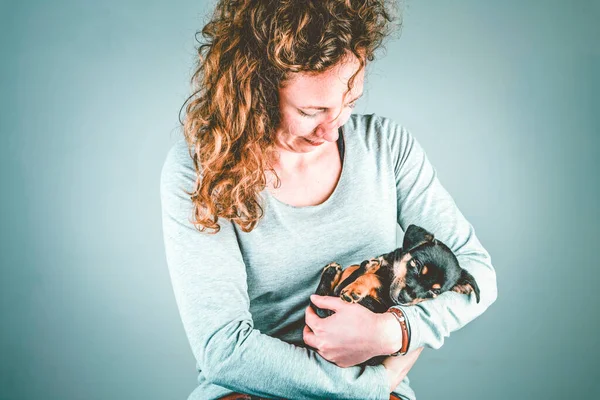 Parte de una hembra, con amor sostiene en sus brazos a un pequeño cachorro Jack Russel Terrier dormido. En verde vintage, colores retro — Foto de Stock