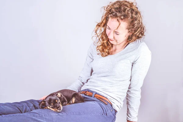 Detalle de una hermosa mujer con el pelo castaño rizado, sentada sonriendo con un cachorro Jack Russel Terrier en sus piernas. Vintage, colores retro — Foto de Stock