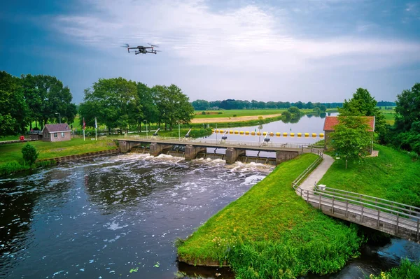 Water swirls from the weir in the river Vecht in the Netherlands. Downstream, Lock Keepers House next to the bridge. Fish passage, fish ladder to the right of the water, Overijsselse Vecht, A flying