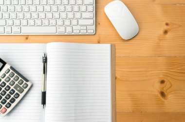 Üstten Görünüm çalışma alanı boş defter, kalem, hesap makinesi klavye ve fare üstünde ahşap masa arka plan ile.