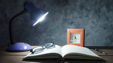 Defter, kalem, saat ve gözlük duvar arka plan ile ahşap masa lambası.