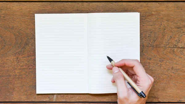 Man handen met pen op lege Kladblok schrijven over houten tafel. — Stockfoto