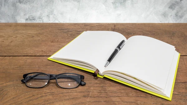 Cuaderno en blanco con bolígrafo y vasos sobre mesa de madera . —  Fotos de Stock