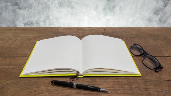 Cuaderno en blanco con bolígrafo y vasos sobre mesa de madera . —  Fotos de Stock