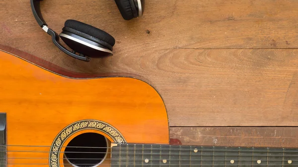 Bovenaanzicht werkruimte met hoofdtelefoon en akoestische gitaar op houten tafel achtergrond. Vrije ruimte voor uw tekst. — Stockfoto