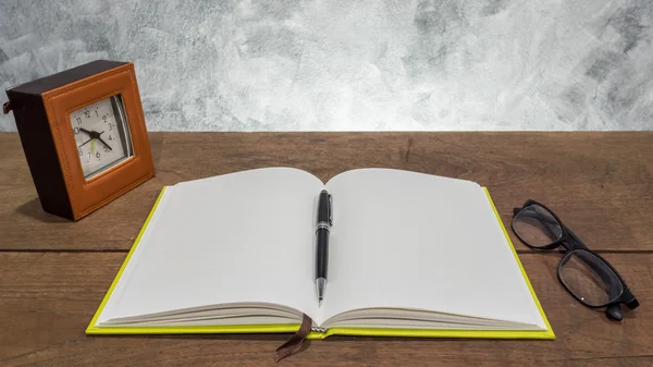 Cuaderno en blanco con bolígrafo, reloj y vasos sobre mesa de madera . —  Fotos de Stock