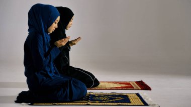 Geleneksel tesettürdeki iki Asyalı Müslüman kadın Allah 'ı yücelterek camide ibadet ediyorlar..