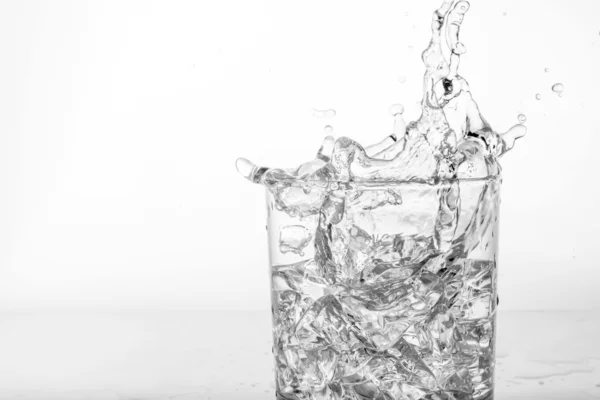 Splashing of water with ice in glass — Stock Photo, Image
