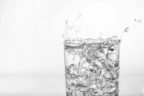 Splashing of water with ice in glass — Stock Photo, Image