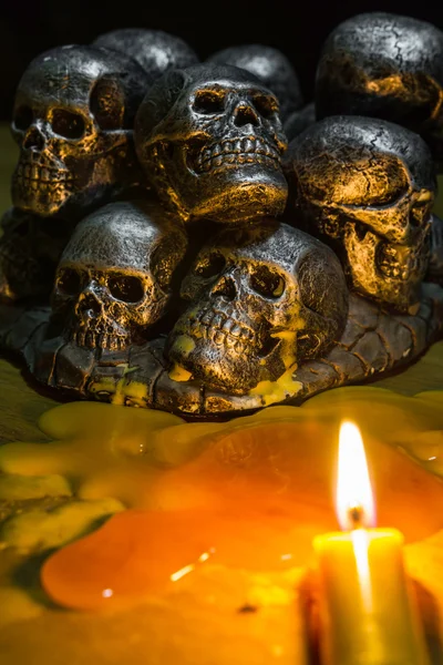 Crânios com vela queimando no fundo de madeira na escuridão — Fotografia de Stock