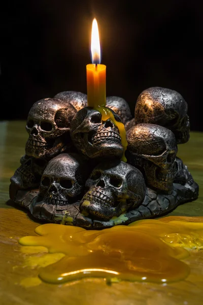 Crânios com vela queimando no fundo de madeira na escuridão — Fotografia de Stock