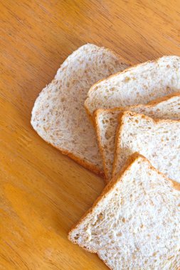 Kepekli ekmek ahşap masanın üzerine dilimlenmiş.