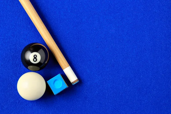 Bolas de billar, taco y tiza en una mesa de billar azul . — Foto de Stock