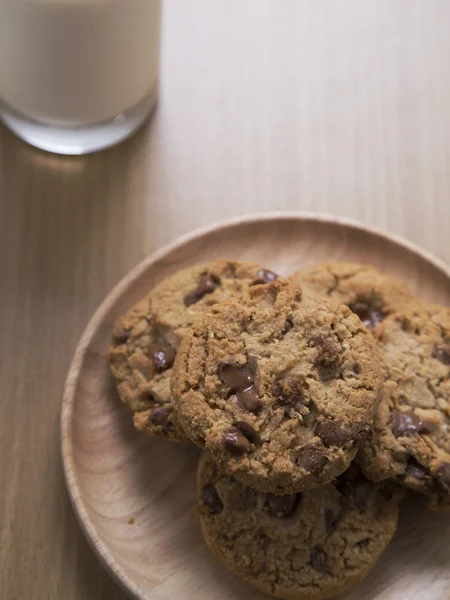 Čokoláda čip cookies na dřevěné desce s sklenici mléka — Stock fotografie