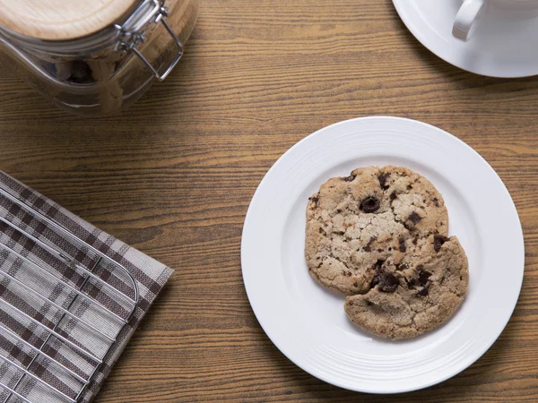 Шоколадное печенье на белой тарелке с банкой для печенья и кофе — стоковое фото