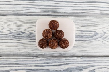 Çiğ vejetaryen tatlıları. Enerji topları hurma, fındık ve kurutulmuş meyvelerden yapılır. Hafif ahşap arka planda vejetaryen yuvarlak şekerler. Seçici odak, üst görünüm, kopyalama alanı.