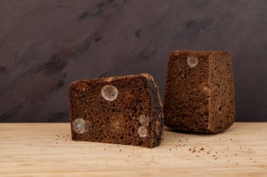 Rye bread with mold, close-up. Improper storage of the products. Concept-reduction of organic food waste. Brown background, copy space.