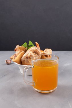 Bone broth in clear mug. Dark background, selective focus, copy space. Beef bones are source of natural collagen, which is useful for joints and provides body with essential amino acids.