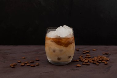 Arka planda hindistan cevizi sütü ve buzlu kahve. Kavrulmuş kahve çekirdekleri masaya saçılmış. Seçici odak, boşluğu kopyala.