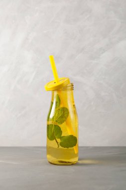 Tazeleyici yaz içeceği. Limonlu mojito kokteyli, limon ve nane şekeri ve sarı cam şişe. Gri arkaplan, kopyala.